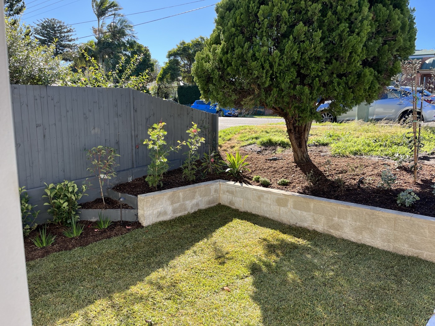 After: finished retaining wall with planted garden beds and new lawn